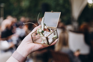 Wedding ceremony. Young girl holds a glass box with wedding rings in her hand