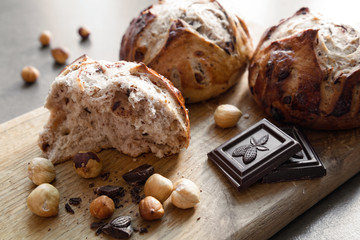 Broken buns with nuts and chocolate on a cutting board close up view. Homemade pastry