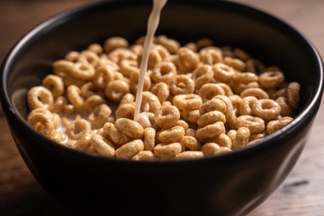 Zdjęcie płatków śniadaniowych z mlekiem w czarnej misce na drewnianym stole