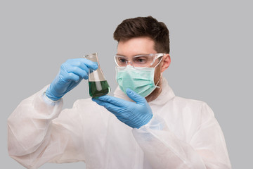 Male Laboratory Worker in Chemical Suit, Wearing Medical Mask and Glasses Watching Flask with Colorfull Liquid. Science, Medical, Virus Concept