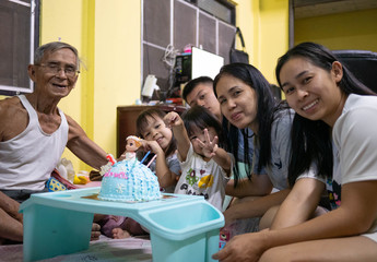 Happy family celebrating birthday to little daughter at home. Cute little girl blowing birthday cake. Concept of happy family and childhood.