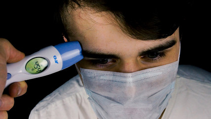 the man in the mask with electric thermometer
