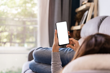 Young woman lying on sofa at living room and using cell phone at home