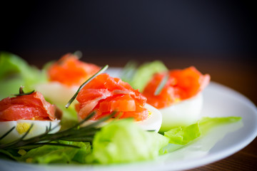 boiled eggs with salted red fish and salad leaves
