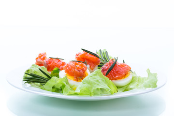 boiled eggs with salted red fish and salad leaves