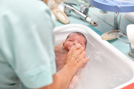 A nurse gives the first bath of a newborn boy