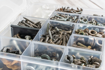 Screws, bolts, nuts and other carpenter stuff in a plastic toolbox (hardware organizer). Stock photo.