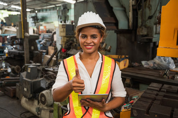 Female industrial worker working and checking machine in a large industrial factory with many equipment.
