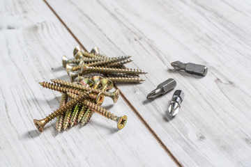 Metal Screws with screwdriver heads (bits) on wooden background. Close up stock photo.