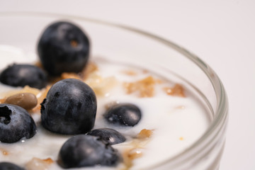 Blueberries in vegan yogurt in a transparent glass, healthy breakfast. Add the berry-shaped vitamins to the milk dessert. Close-up