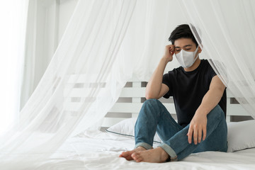 Asian man wearing Face Mask to protect  feeling sick headache and cough because of Coronavirus covid-19 in quarantine room , Quarantine yourself to protect spread Covid-19 Coronavirus