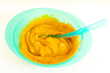 Pureed baby food in blue plastic plate. Vegetable, carrots, potato and meat mashed for babies. White bright background.