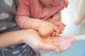 Mother helping her kid washing hands with water and liquid soap - Teaching baby clean and healthy manners against bacteria - Personal hygiene	