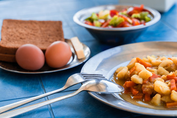 Simple Rustic Food Breakfast Set. Stewed Potatoes with Carrots, Vegetable Salad, Boiled Eggs, Bread and Butter. Stock Photo.