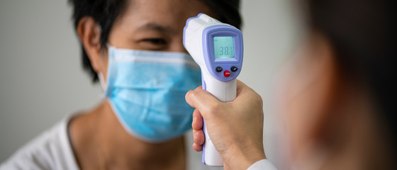 Female doctor check Asian woman body temperature using infrared forehead thermometer (thermometer...