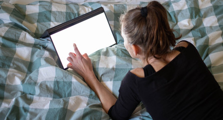 woman using laptop or tablet in bed white empty screen for copy space