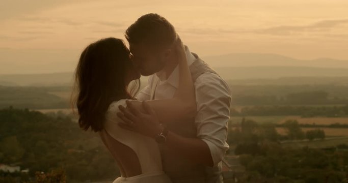 Couple kissing and embracing in sunlight. Loving couple face to face kissing and hugging. Real-time, hand-held shot, close up, 4K.