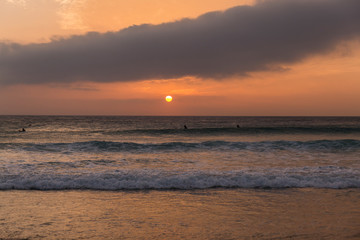 Obraz premium sunset on the beach, sky with orange colors and clouds, sea with small waves