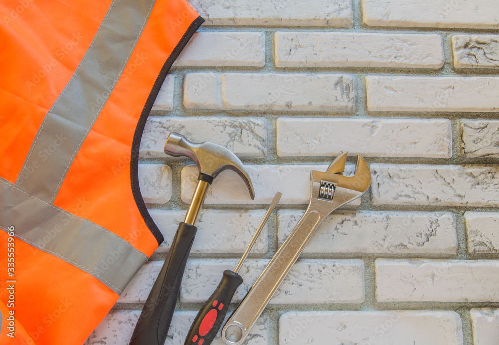 Wall mural Orange construction vest and tool kit on a brick gray background with a copy of the space, Builder's Day, engineer's Day, labor Day