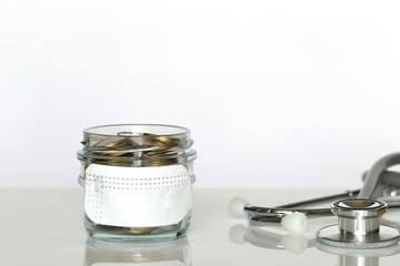 Stack of coins money in glass bottle with wearing protective medical mask on white background,Save money for Medical insurance and Health care concept