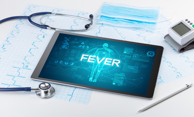 Tablet pc and doctor tools with FEVER inscription, coronavirus concept