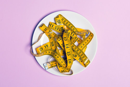 White plate with yellow measuring tape on the table
