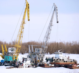 Fototapeta na wymiar Harbor cranes in the winter. Off-season for port and floating cranes. End of work for the river and navy
