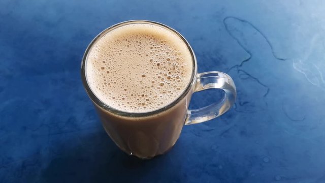 (Teh Tarik) in a transparent cup on a blue table. Tea with milk drinks is popular in Asia. (Selective Focus)
