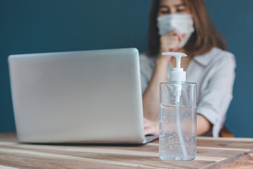 The alcohol gel is placed on the desk of an Asian businesswoman. An Asian businesswoman is sick while working in her office.