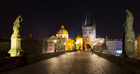 Fototapeta na wymiar Night colorful Prague Old Town with Bridge Tower and St. Francis of Assisi Cathedral from Charles Bridge with its baroque Statues without People at the time of Coronavirus, Czech republic