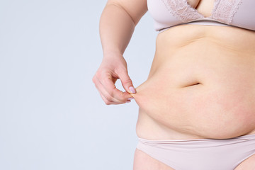 Tummy tuck, flabby skin on a fat belly, plastic surgery concept