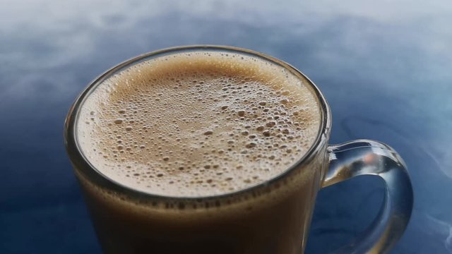 (Teh Tarik) in a transparent cup on a blue table. Tea with milk drinks is popular in Asia. (Selective Focus)