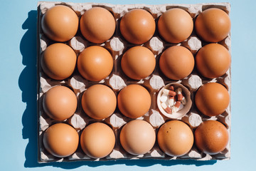 box with chicken eggs on a blue background. pills in
egg shell. concept idea health