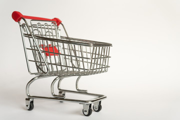 Empty supermarket consumer food trolley from steel with red plastic handle on a gray background...