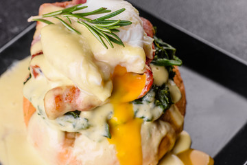 Eggs benedict or eggs florentine on a black plate in the cafe