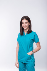 Vertical portrait of a young smiling medical student or female doctor holding hand in pocket on white background.