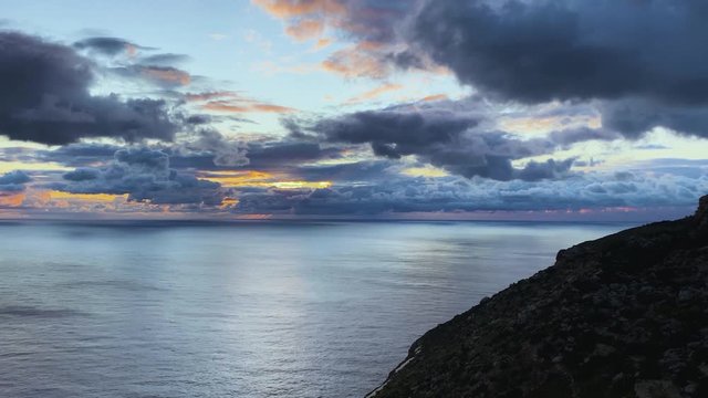 Beautiful fluffy large clouds covering the sun on the ocean horizon. timelapse of the romantic sunset