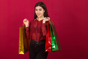 Fototapeta na wymiar beautiful young woman with packages in hands on a red background