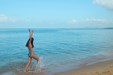 A happy young girl has her hands up and is having fun at the sea on a summer lifestyle vacation. Active recreation at the resort. Freedom and pleasure and good mood