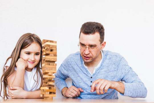 Girl and dad play a game at home, cost a tower of blocks, cubes, jenga, puzzle for brain development, mental intelligence, child development, school, home, quarantine, vacation, time with family