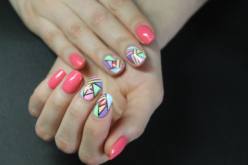 Fashionable manicure gel Polish on natural nails with abstract bright and geometric design on the hands of a modern girl