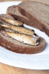 Canned sprats on rye bread served with herb baked potatoes