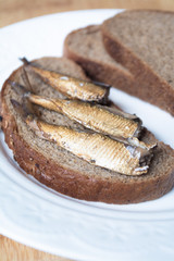 Canned sprats on rye bread served with herb baked potatoes