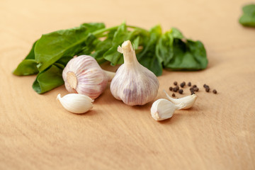 Garlic, spinach leaves and peper on a wooden background
