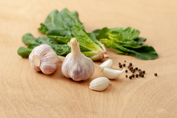 Garlic, spinach leaves and peper on a wooden background