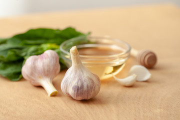 Garlic, spinach leaves and honey on a wooden background
