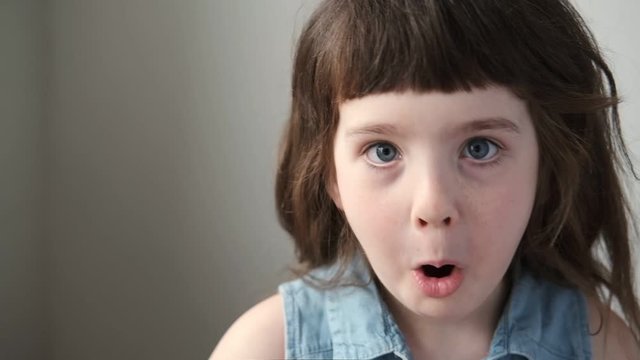 A 6-7 year old girl makes faces and makes faces. Close up.