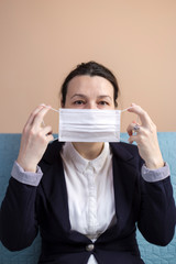 Business woman putting on his medical mask sitting on sofa