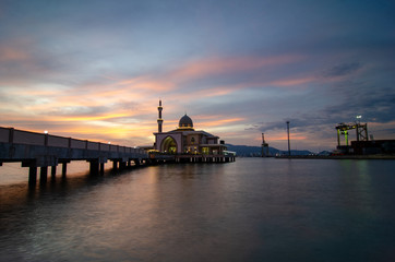 Fototapeta na wymiar Butterworth, Malaysia floating mosque with dramatic sunset cloud with container terminal as background.