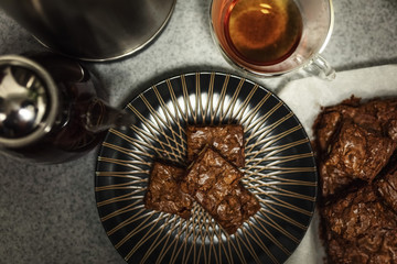 Sweet composition: chocolate brownie cake on a dark plate standing on a gray table. The concept of home baking with your own hands. Selective focus.